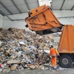 a man standing next to a pile of trash